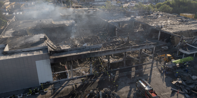 Ukrainian State Emergency Service firefighters work to take away debris at a shopping center burned after a rocket attack in Kremenchuk, Ukraine, on Tuesday, June 28.