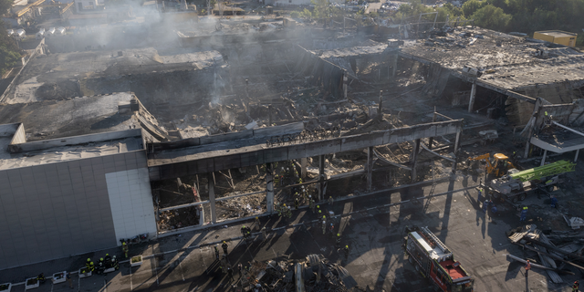 Ukrainian State Emergency Service firefighters work to take away debris at a shopping center burned after a rocket attack in Kremenchuk, Ukraine, on Tuesday, June 28.