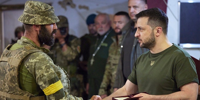 Ukrainian President Volodymyr Zelenskyy, right, awards a serviceman as he visits the war-hit Mykolaiv region of Ukraine June 18, 2022. 