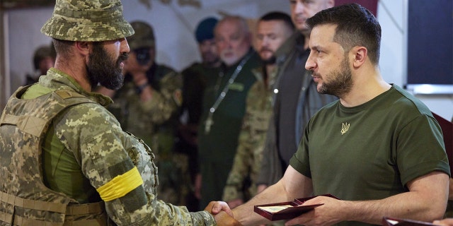 In this photo provided by the Ukrainian Presidential Press Office on Saturday, June 18, 2022, Ukrainian President Volodymyr Zelenskyy, right, awards a serviceman as he visits the war-hit Mykolaiv region.