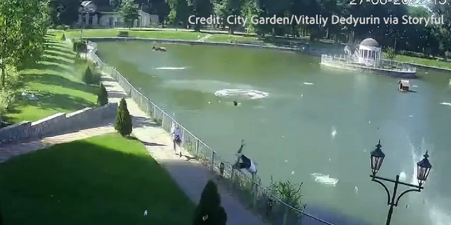 A Ukrainian is seen leaping into a pond as debris starts falling from the sky.