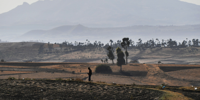 A man is the silhouette of a patchwork of harvested teff cornfields near the crash site of an Ethiopian airliner, which was operated by a Boeing 737 MAX aircraft on March 16, 2019 in the village of Hama Quntushele near Bishoftu in the Oromia region. 