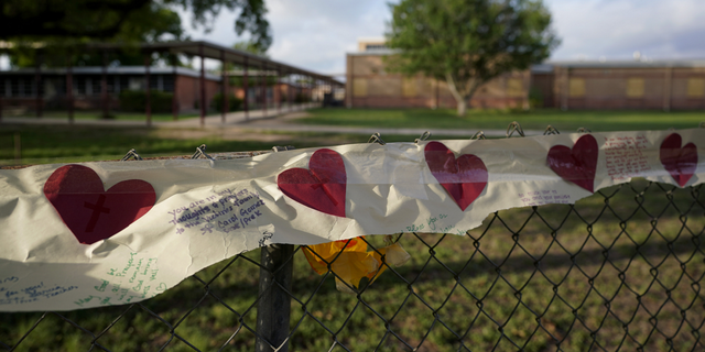 Hearts on a banner hang on a fence at a boarded up Robb Elementary School on Friday, June 3.