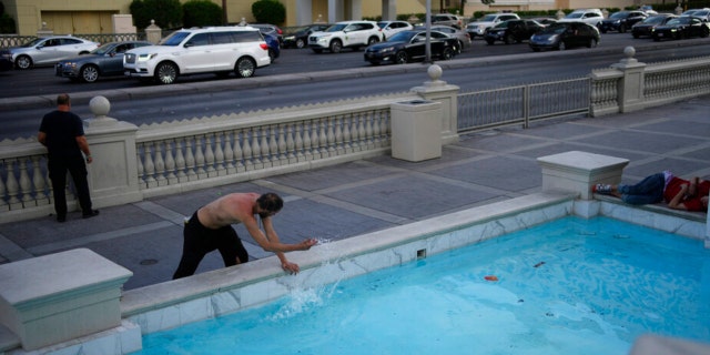 A homeless man cools off in fountain along the Las Vegas Strip in Las Vegas on Thursday, May 26, 2022. Hundreds of homeless people die in the streets each year from the heat, in cities around the U.S. and the world.