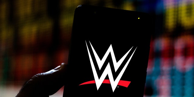 The World Wrestling Entertainment (WWE) logo is seen on a smartphone in a photo illustration.