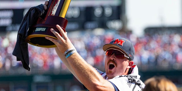 Mississippi's Tim Elko holds the trophy while celebrating a win over Oklahoma in Game 2 of the NCAA College World Series baseball finals, Sunday, June 26, 2022, in Omaha, Neb. 