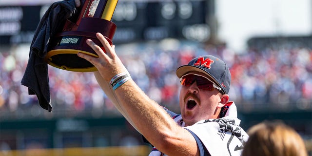 Mississippi's Tim Elko holds the trophy while celebrating a win over Oklahoma in Game 2 of the NCAA College World Series baseball finals, Sunday, June 26, 2022, in Omaha, Neb.