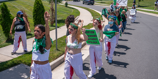 Abortion-rights activists with Rise Up 4 Abortion Rights chant after marching to the home of Supreme Court Justice Amy Coney Barrett on June 18, 2022 in Falls Church, Virginia. According to the Rise Up 4 Abortion Rights group, the dolls represent forced births. (Photo by Nathan Howard/Getty Images)