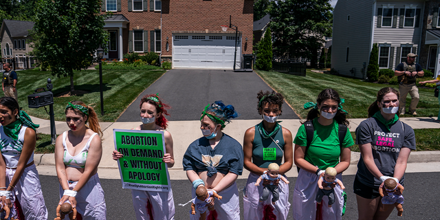 Abortion-rights activists with Rise Up 4 Abortion Rights chant after marching to the home of Supreme Court Justice Amy Coney Barrett on June 18, 2022, in Falls Church, Virginia. According to the Rise Up 4 Abortion Rights group, the dolls represent forced births. (Photo by Nathan Howard/Getty Images)