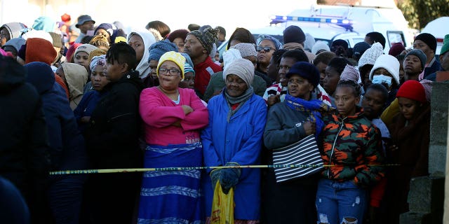 People stand behind a police cordon outside a nightclub in East London, South Africa, Sunday June 26, 2022. 