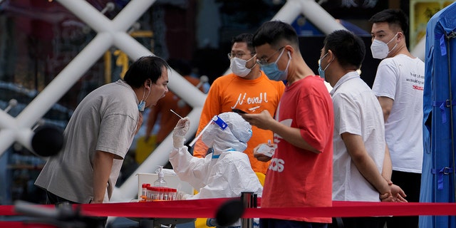 Residents get swabbed during mass COVID-19 testing in the Chaoyang district in Beijing, Tuesday, June 14, 2022. Authorities ordered another round of three days of mass testing for residents in the Chaoyang district following the detection of hundreds coronavirus cases linked to a nightclub. (AP Photo/Andy Wong)