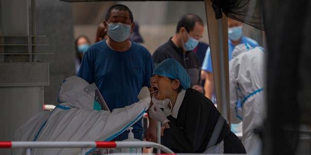 Residents get swabbed at a COVID-19 testing site in the Chaoyang district in Beijing, Tuesday, June 14, 2022. Authorities ordered another round of three days of mass testing for residents in the Chaoyang district following the detection of hundreds coronavirus cases linked to a nightclub.