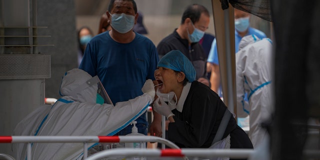 Residents get swabbed at a COVID-19 testing site in the Chaoyang district in Beijing, Tuesday, June 14, 2022. Authorities ordered another round of three days of mass testing for residents in the Chaoyang district following the detection of hundreds coronavirus cases linked to a nightclub.