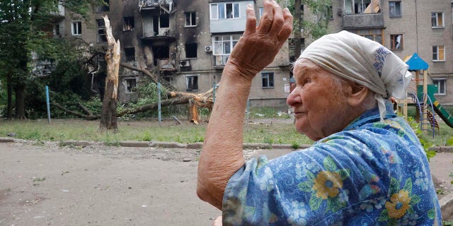 A woman gestures near an apartment building damaged during shelling in Donetsk, in territory under the government of the Donetsk People's Republic, eastern Ukraine, Wednesday, June 22, 2022.