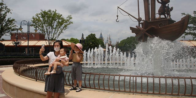 Visitors take photos outside the Disney Resort theme park, Thursday, June 30, 2022, in Shanghai. Shanghai is moving to allow in-person dining and reopening its Disney Resort theme park as domestically transmitted cases of COVID-19 in China's largest city remain at zero following a more than two-month lockdown. 