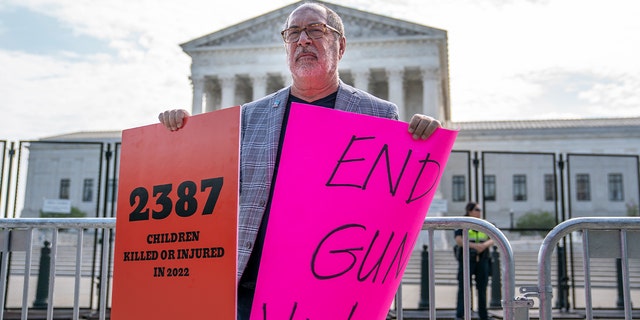 A protester holds signs calling for an end to gun violence in front of the Supreme Court on June 8, 2022 in Washington, DC. The court is expected to announce a series of high-profile decisions this month.  
