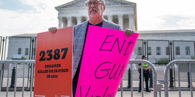 A protester holds signs calling for an end to gun violence in front of the Supreme Court on June 8, 2022 in Washington, DC.