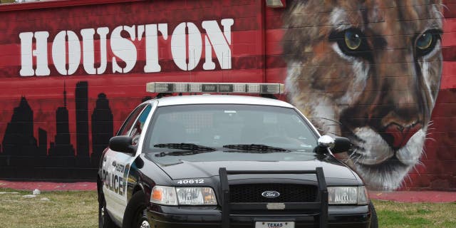 Un coche de policía de Houston frente a un edificio cubierto de graffiti en la sección Old Chinatown del centro de la ciudad, cerca del Centro de Convenciones George R. Brown.