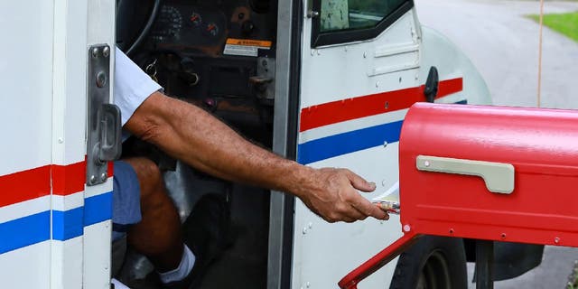 A mailman reaches out of his truck to deliver mail, Oct. 2, 2021, in Fort Lauderdale, Florida.