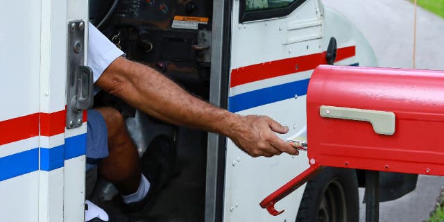 A mailman reaches out of his truck to deliver mail, Oct. 2, 2021, in Fort Lauderdale, Florida.