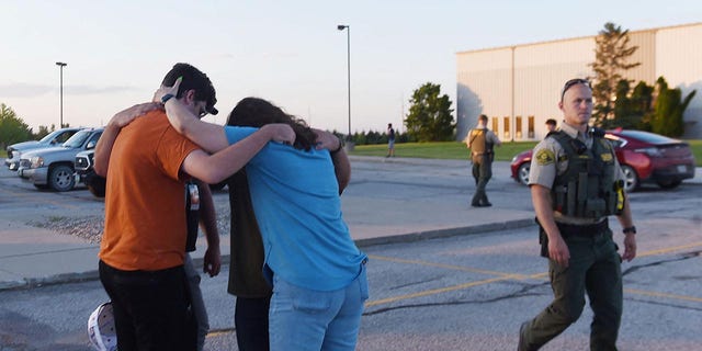 مردم پس از تیراندازی در کلیسای کرنرستون در ایمز، آیووا، ایالات متحده در 2 ژوئن 2022 در پارکینگ کلیسای باپتیست CrossRoad دعا می کنند. تصویر در 2 ژوئن 2022 گرفته شده است.  