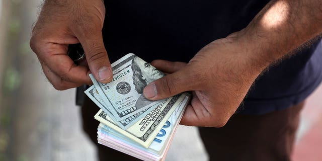 A street money exchanger poses for a photo without showing his face as he counts foreign banknotes on Ferdowsi street, Tehran's go-to venue for foreign currency exchange, Sunday, June 12, 2022.