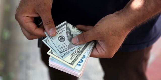 A street money exchanger poses for a photo without showing his face as he counts foreign banknotes on Ferdowsi street, Tehran's go-to venue for foreign currency exchange, Sunday, June 12, 2022.