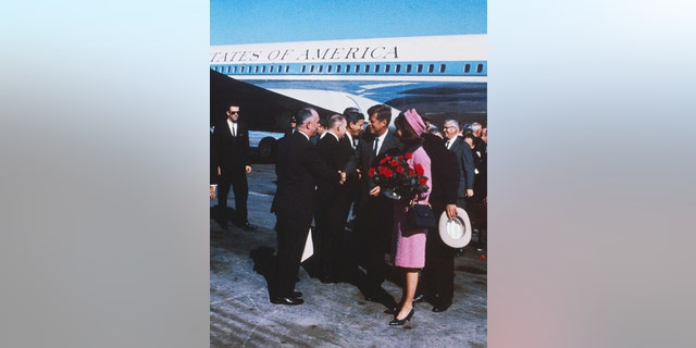 President John F. Kennedy and First Lady Jackie Kennedy, seen holding a bouquet of red roses, arrive in Dallas, Texas. November 22nd, 1963. (Bettman/Getty Images)