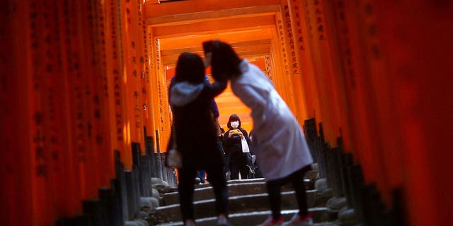 Visitors, wearing masks after the outbreak of the coronavirus disease (COVID-19), explore the wooden torii gates of the Fushimi Inari Taisha Shinto shrine in Kyoto, Japan, March 13, 2020. REUTERS/Edgard Garrido/File Photo