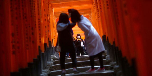 Visitors, wearing masks following the outbreak of the coronavirus disease (COVID-19), explore the wooden torii gates at Fushimi Inari Taisha shinto shrine in Kyoto, Japan March 13, 2020. REUTERS/Edgard Garrido/File Photo