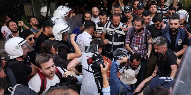 Police officers prevent journalists from taking photographs of detained activists while trying to film and march in a Pride Parade that was banned by local authorities on June 26, 2022, in central Istanbul, Turkey.  (Reuters/Umit Bektas)
