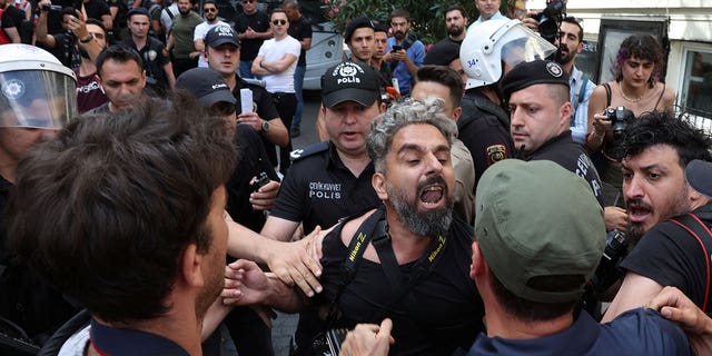 Agentes de policía impiden que los periodistas filmen y tomen fotos de activistas detenidos mientras intentan participar en un desfile del Orgullo, prohibido por las autoridades locales, en el centro de Estambul, Turquía, el 26 de junio de 2022. (REUTERS/Umit Bektas)