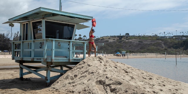 Ocean lifeguard Tiana Pugliese makes her way down from a lifeguard tower at Zuma Beach in Malibu, California, on August 20, 2021. (Mel Melcon / Los Angeles Times via Getty Images)