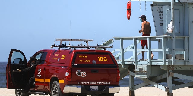 A lifeguard wears a face mask on Santa Monica beach on the day Los Angeles County reopened its beaches, which had been closed due the coronavirus pandemic, on May 13, 2020 in Santa Monica, California. (Photo by Mario Tama/Getty Images)