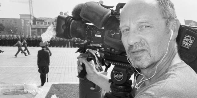 Mal James holding his camera while on assignment.