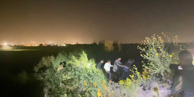 A group of migrants is led out of the brush and to a main road near Hidalgo, Texas by Texas National Guard. 