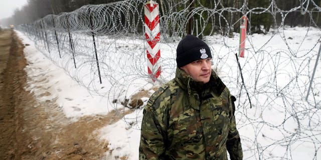 A military person patrols the start of the work on the first part of a 180 kilometers (115 miles) and 5.5 meter (18ft)-high metal wall intended to block migrants from Belarus crossing illegally into EU territory, in Tolcze, near Kuznica, Poland, Jan. 27, 2022. A year after migrants started crossing into the European Union from Belarus to Poland, Polish authorities are planning to announce Thursday that a 5.5-meter-tall steel wall along its border to the north with Belarus is set to be completed.