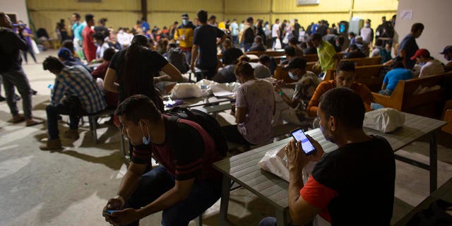 People wait at a warehouse run by the Mission: Border Hope nonprofit group, in Eagle Pass, Texas, May 23, 2022. The Border Patrol releases up to 1,000 migrants daily at Mission: Border Hope. The nonprofit group, run by the United Methodist Church, outgrew a church and moved to the warehouse in April amid the Biden administration's rapidly expanding practice of releasing migrants on parole, particularly those who are not subject to a pandemic rule that prevents migrants from seeking asylum.