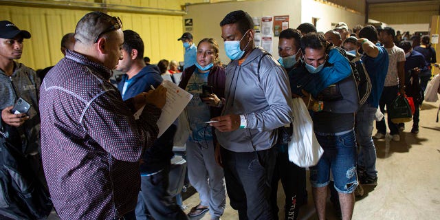 People line up for a commercial bus that will take them to the San Antonio airport at a warehouse run by the Mission: Border Hope nonprofit group run by the United Methodist Church in Eagle Pass, Texas, May 23, 2022.