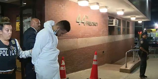 Argenis Baez is led out of NYPD precinct in handcuffs.