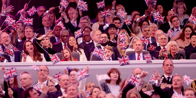 Catherine, Duchessa di Cambridge, Principessa Charlotte di Cambridge, Principe Giorgio di Cambridge, Principe William, Duca di Cambridge sventolano bandiere Union Jack mentre 'Sweet Caroline' suona durante il Platinum Party al Palazzo di fronte a Buckingham Palace.