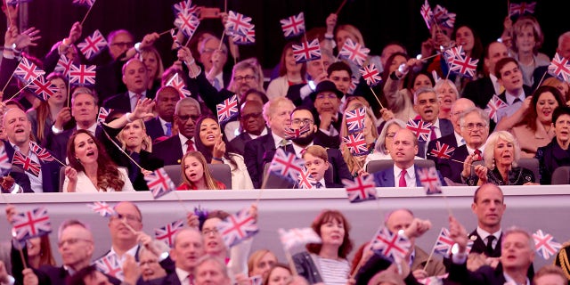 Catherine, Duchess of Cambridge, Princess Charlotte of Cambridge, Prince George of Cambridge, Prince William, Duke of Cambridge wave Union Jack flags as 'Sweet Caroline' plays during the Platinum Party at the Palace in front of Buckingham Palace.