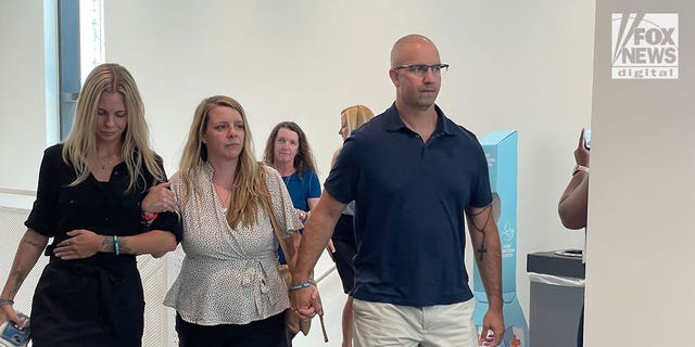 Gabby Petito's mother, Nichole Schmidt, center, seen walking into a Florida courtroom ahead of a hearing on June 22, 2022. Jim Schmidt, Petito's stepfather, holds her hand.