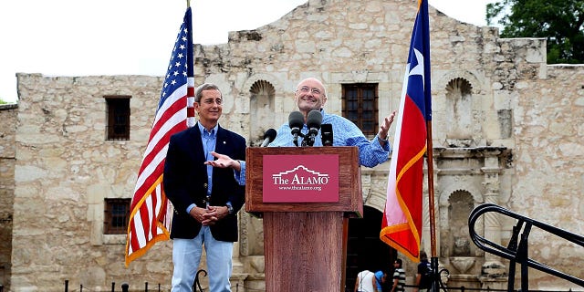 Texas Land Commissioner Jerry Patterson (L) listens as Phil Collins speaks in front of The Alamo, announcing the donation of his collection of historical Alamo artifacts on June 26, 2014 in San Antonio, Texas.