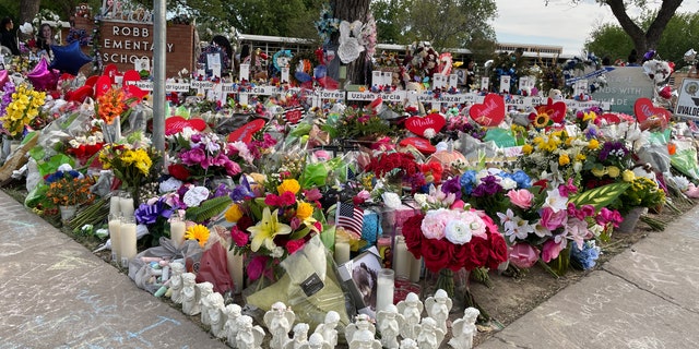 The lawn of Robb Elementary School is now filled with flowers and memorials.