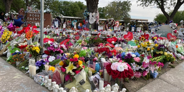 The lawn of Robb Elementary School is now filled with flowers and memorials.