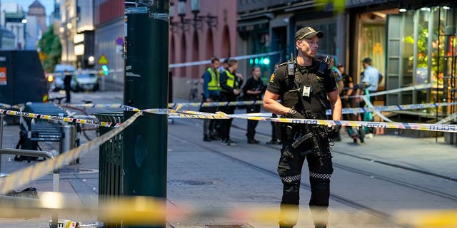 Cảnh sát đứng gác tại địa điểm xảy ra vụ xả súng hàng loạt ở Oslo, rạng sáng thứ Bảy, ngày 25 tháng 6 năm 2022. 