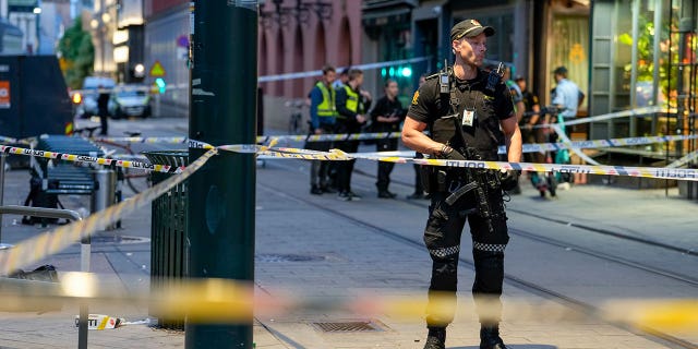 Police stand guard at the site of a mass shooting in Oslo, early Saturday, June 25, 2022. 