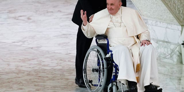 El papa Francisco llega en silla de ruedas para asistir a una audiencia con monjas y superiores religiosos en el salón Pablo VI del Vaticano el 5 de mayo de 2022.