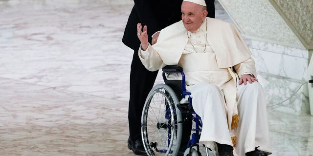 Pope Francis arrives in a wheelchair on May 5, 2022 at Paul VI Hall in Vatican to attend the audience with a nun and a religious boss.